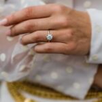 Gold engagement ring with a large round diamond on a woman's finger