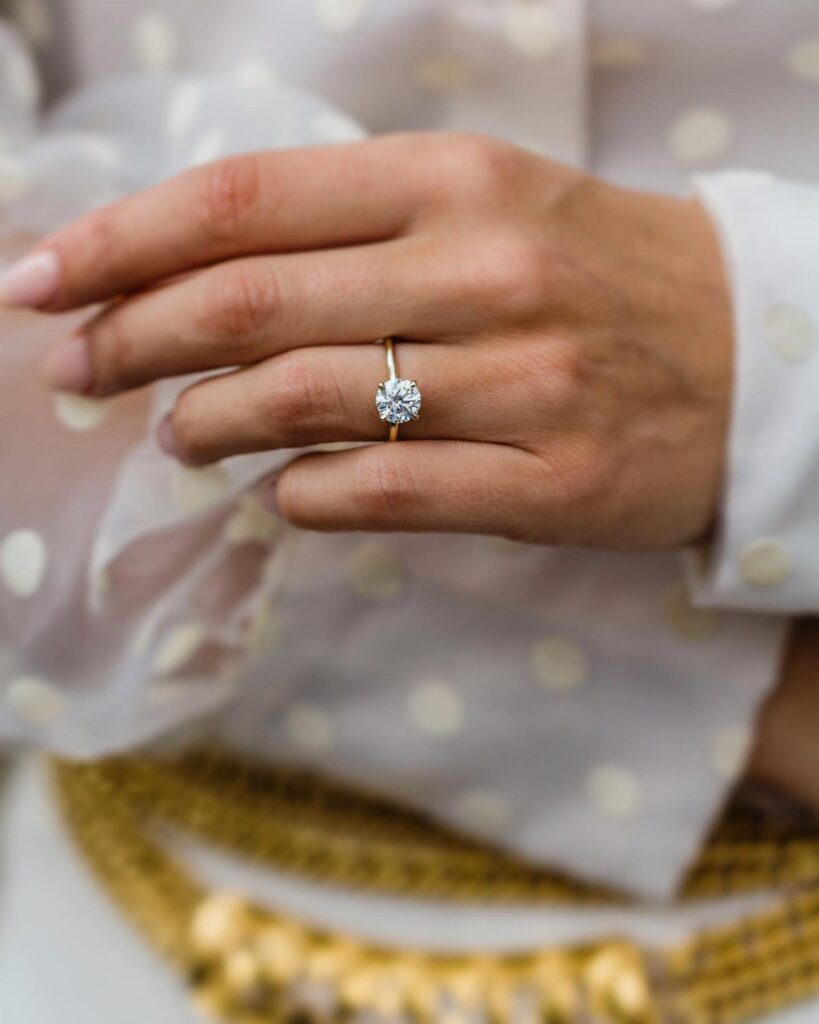 Gold engagement ring with a large round diamond on a woman's finger