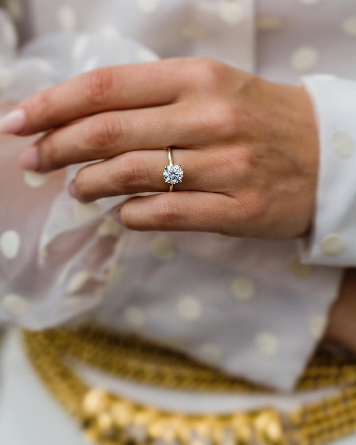 Gold engagement ring with a large round diamond on a woman's finger