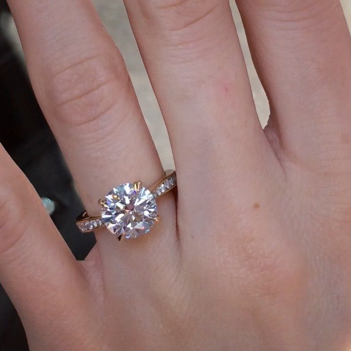 Gold diamond ring with a large center stone on a person's finger