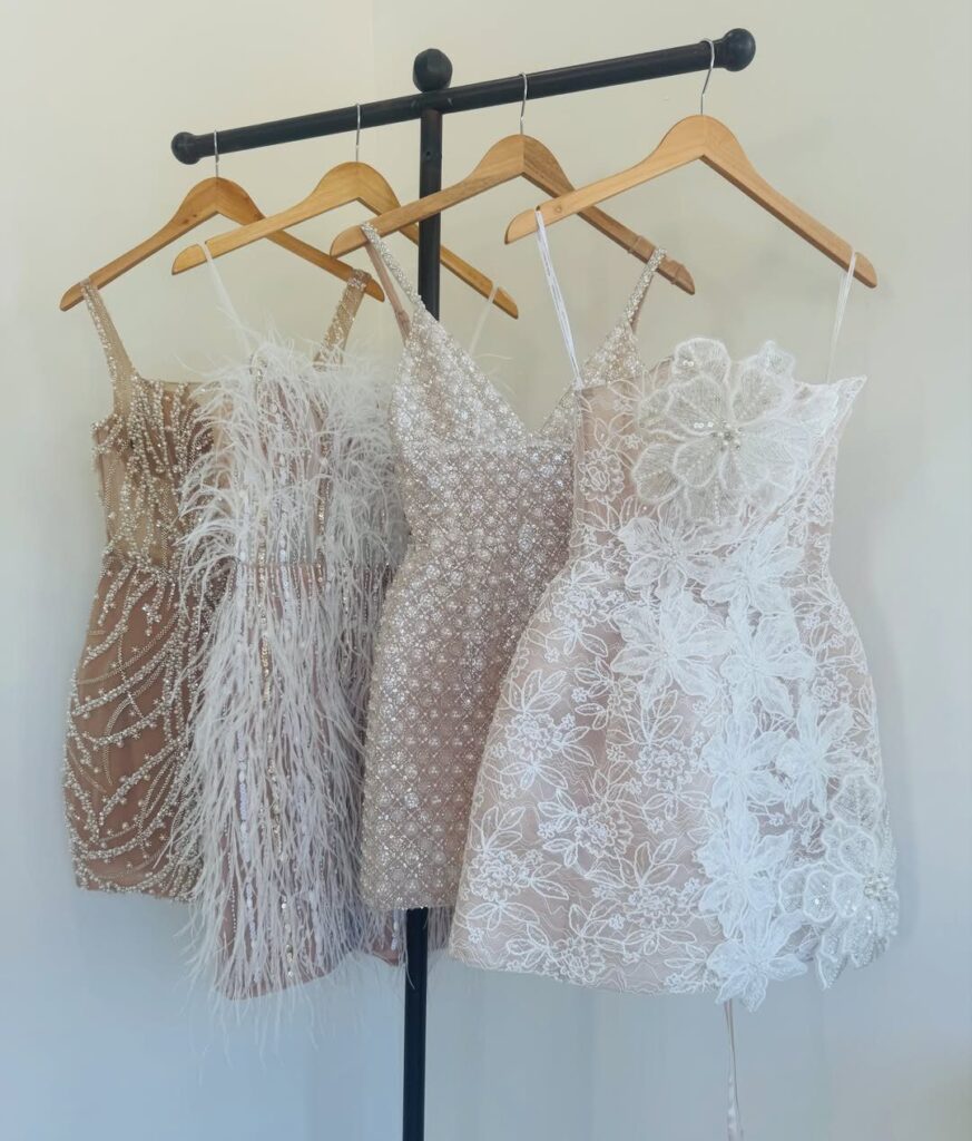 Four short white and champagne wedding after party dresses on a clothing rack