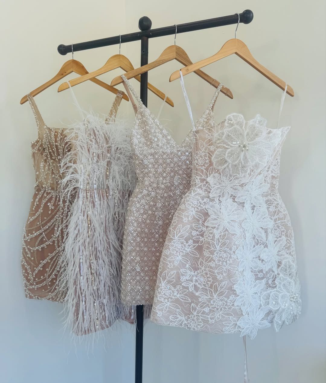 Four short white and champagne wedding after party dresses on a clothing rack