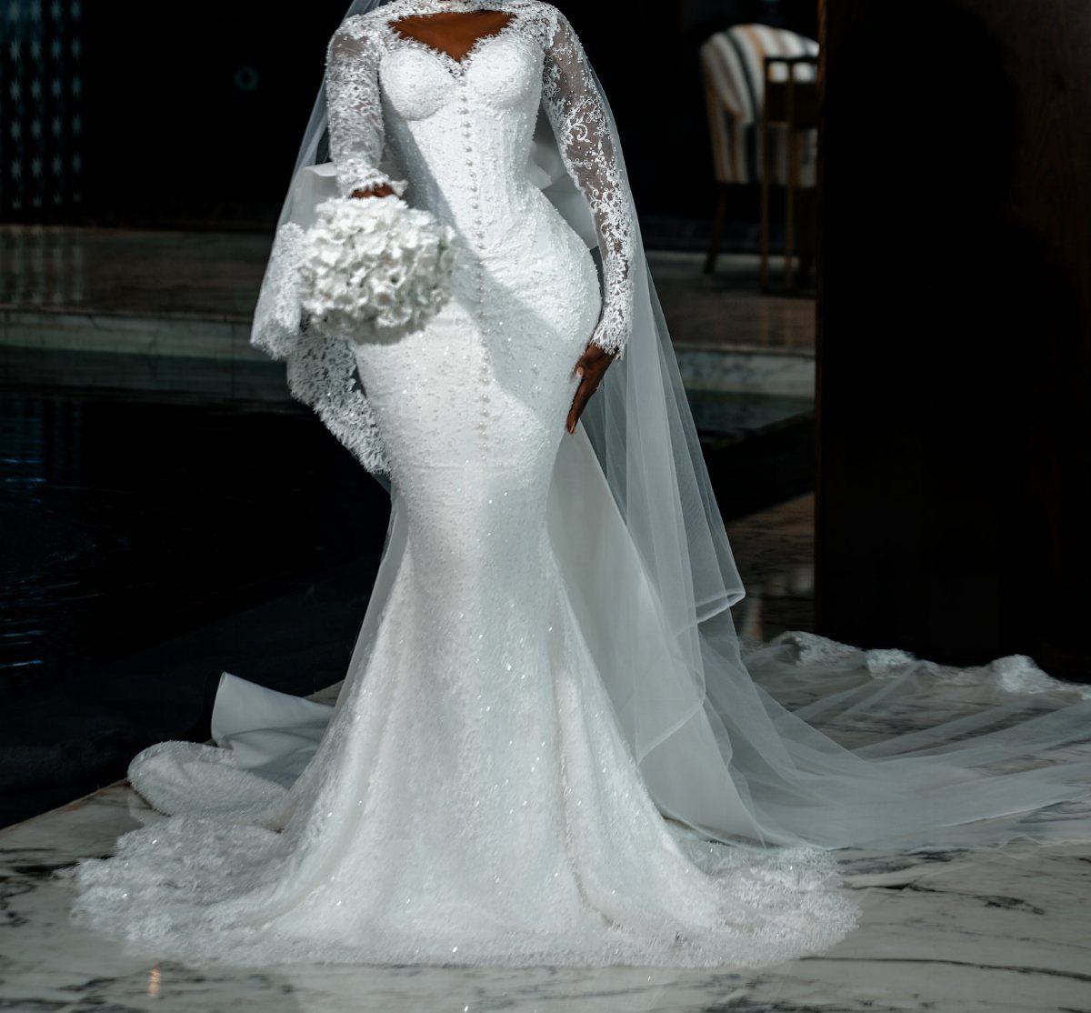 Woman in a white lace mermaid wedding dress holding a white bouquet