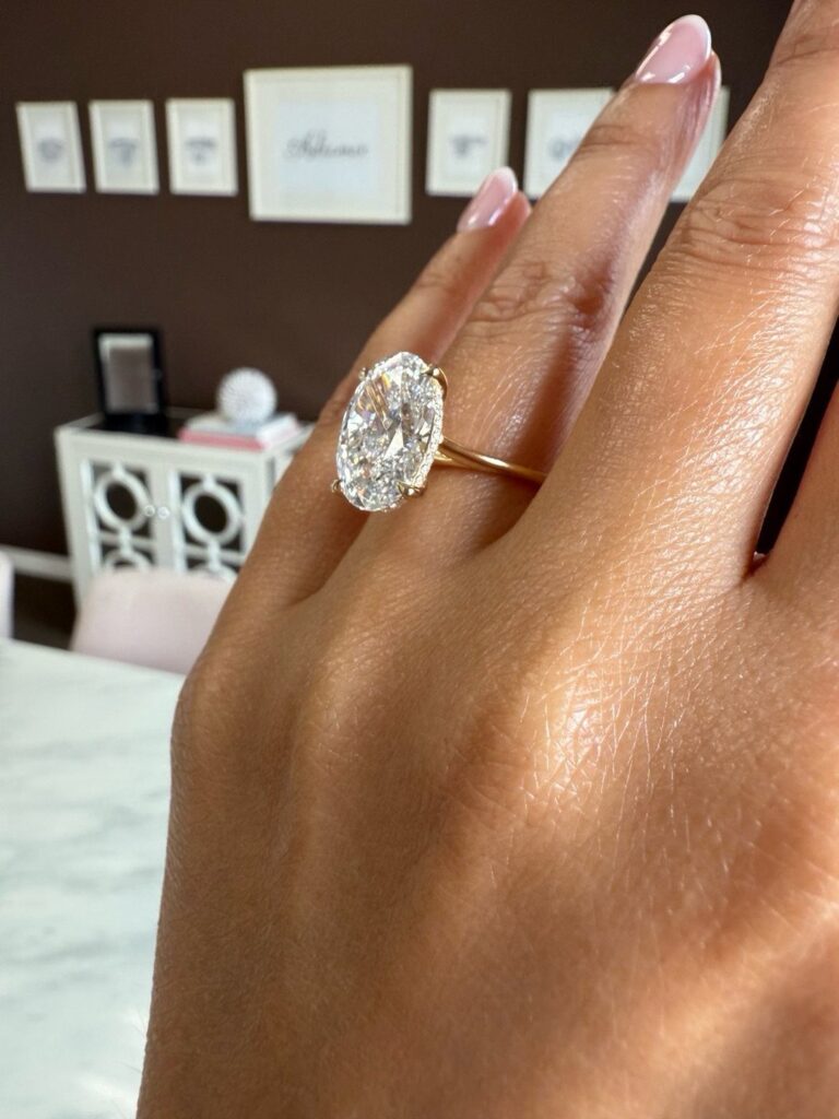 Almond shaped diamond engagement ring on a gold band worn on a finger