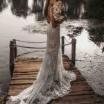 Woman in a white lace wedding dress with a train on a wooden dock