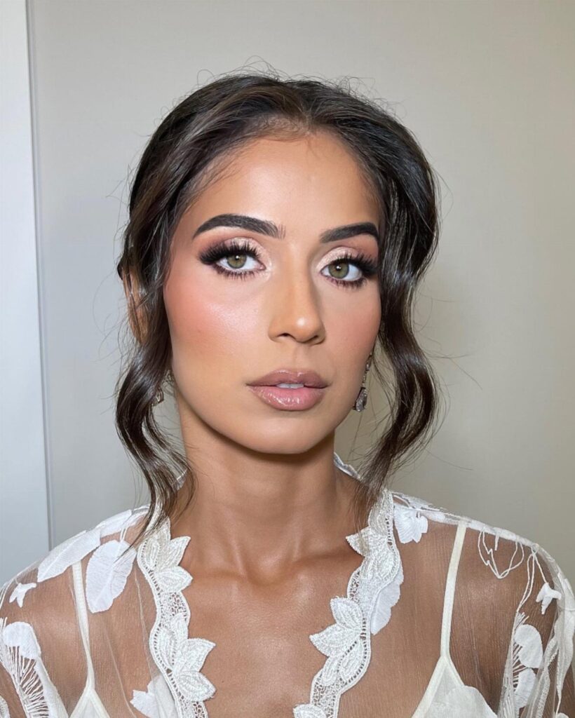 Woman with green eyes wearing bridal makeup and a white lace wedding dress.