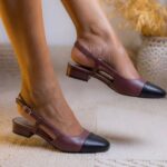 Burgundy and black two-tone slingback pumps with low block heels on a rug.