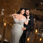 Woman in a sparkling silver beaded gown posing with a man in a suit.