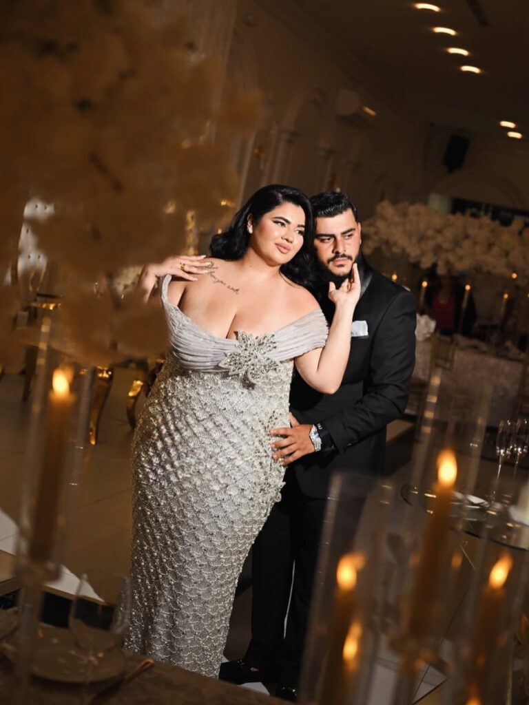 Woman in a sparkling silver beaded gown posing with a man in a suit.