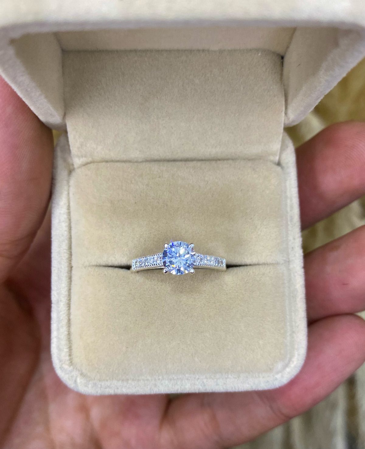 Silver engagement ring with a single large diamond in a beige velvet box