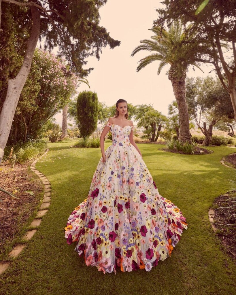 Woman in a white floral ball gown wedding dress standing on a green lawn