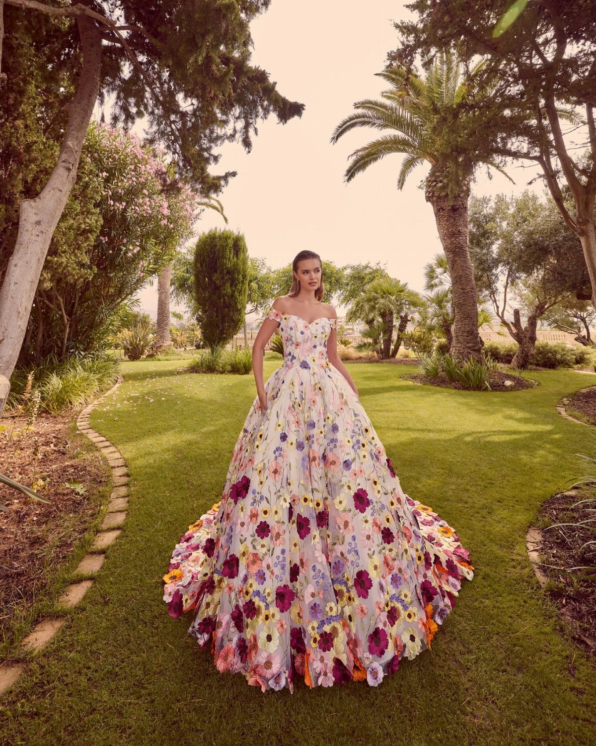 Woman in a white floral ball gown wedding dress standing on a green lawn