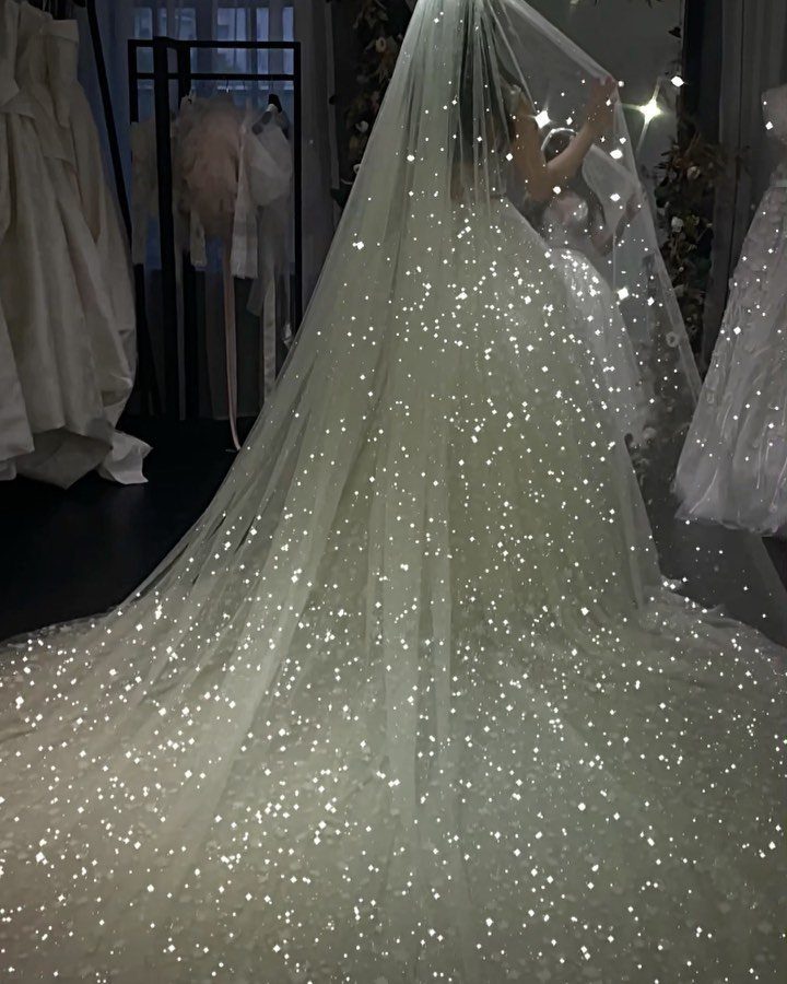 Sparkling white wedding dress and veil covered in shimmering beads in a bridal shop