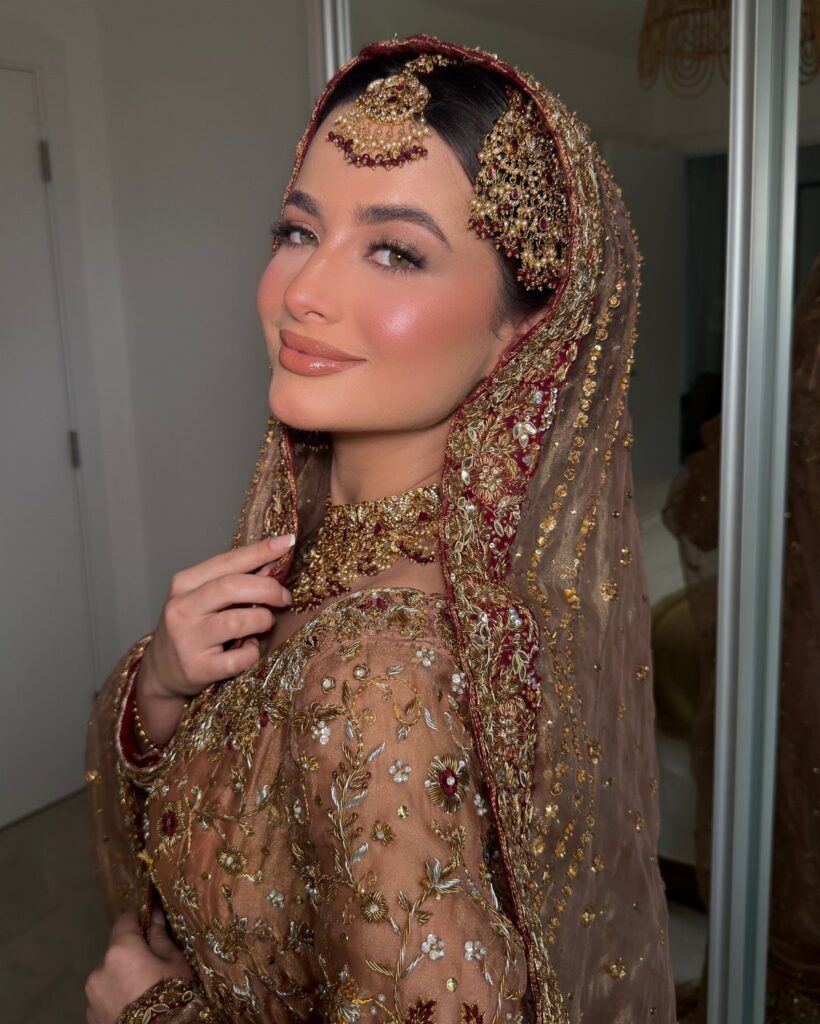 Woman in gold bridal attire with peachy makeup and traditional gold jewelry.