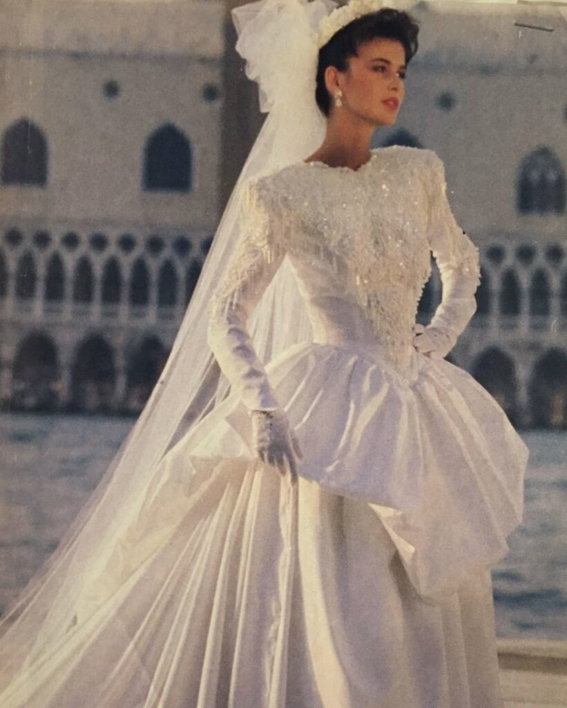 Woman in a vintage white wedding dress with a long veil and beaded bodice.