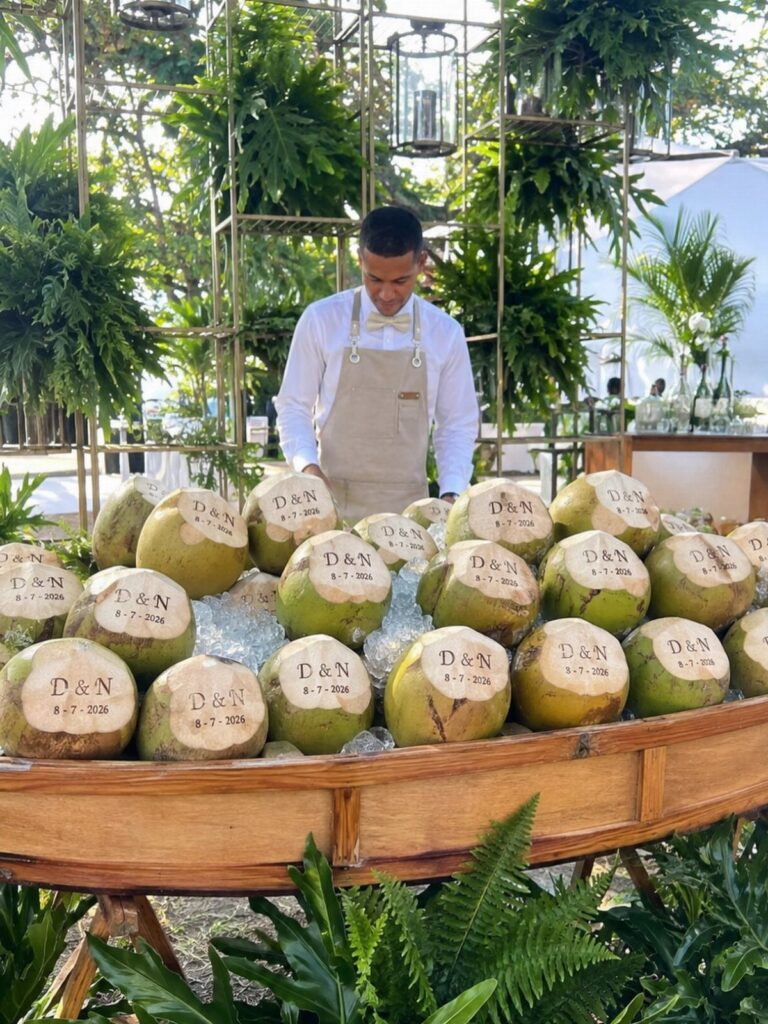 Carved coconuts with initials and date displayed on ice in a wooden boat.