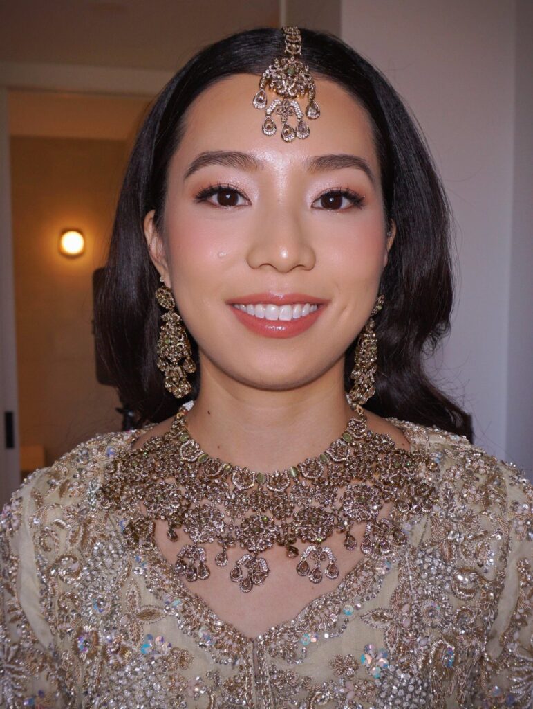 Asian woman with soft glam wedding makeup wearing ornate gold bridal jewelry