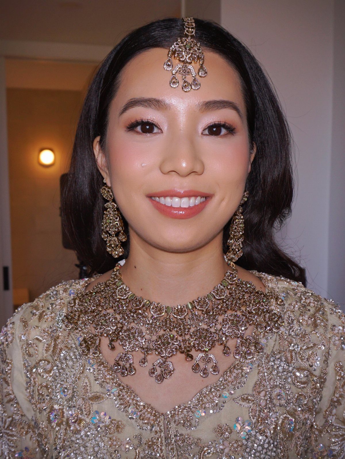 Asian woman with soft glam wedding makeup wearing ornate gold bridal jewelry