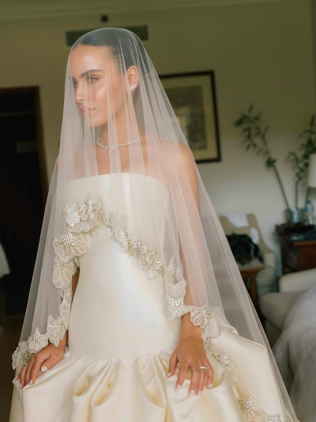 Woman in a cream satin drop waist wedding dress with a lace-edged veil.