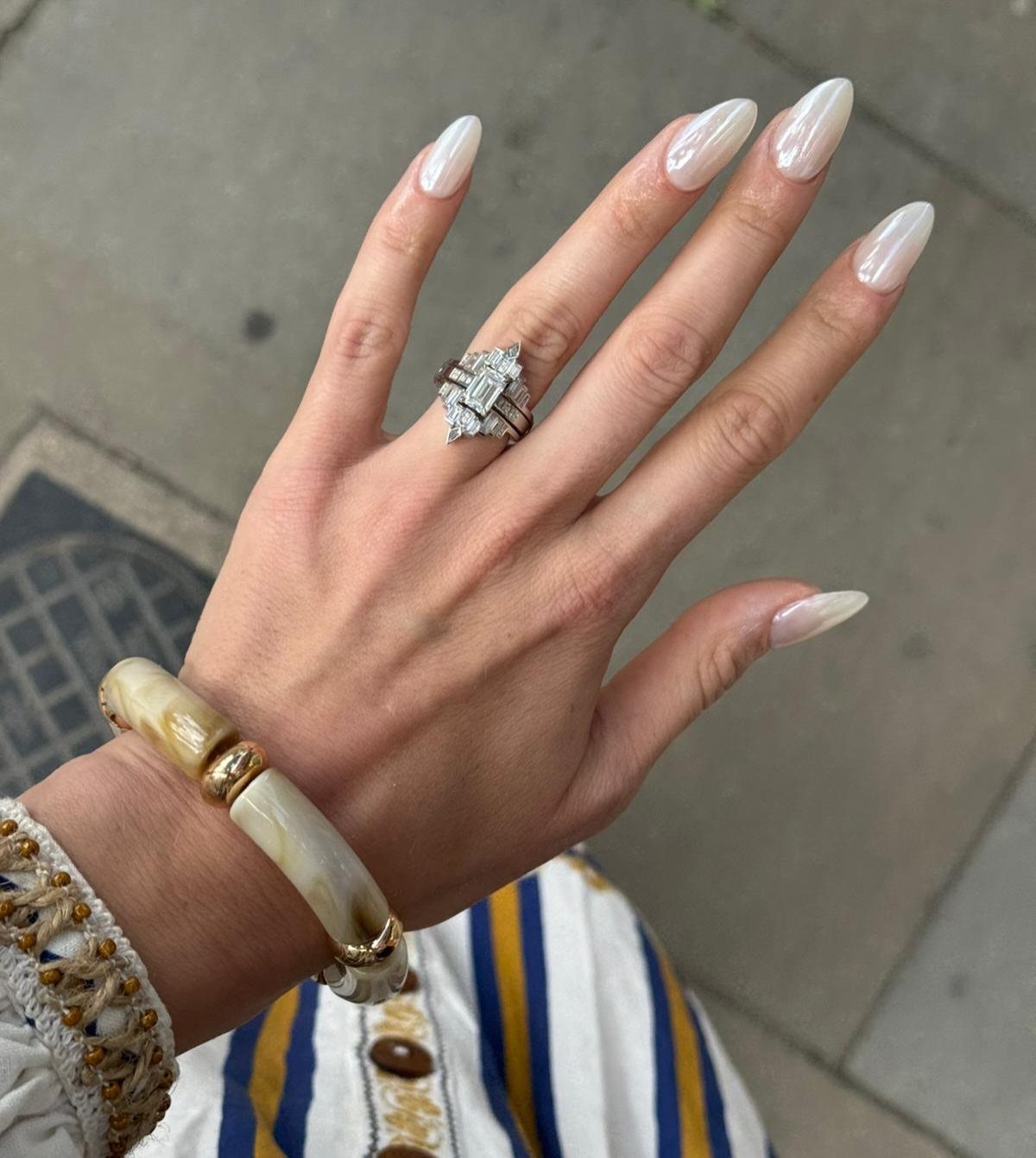 Diamond engagement ring with rectangular center stone on a hand with white nails