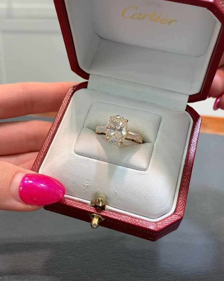 Gold oval diamond engagement ring inside a red Cartier jewelry box