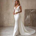 Woman in a simple elegant white wedding dress holding a yellow calla lily