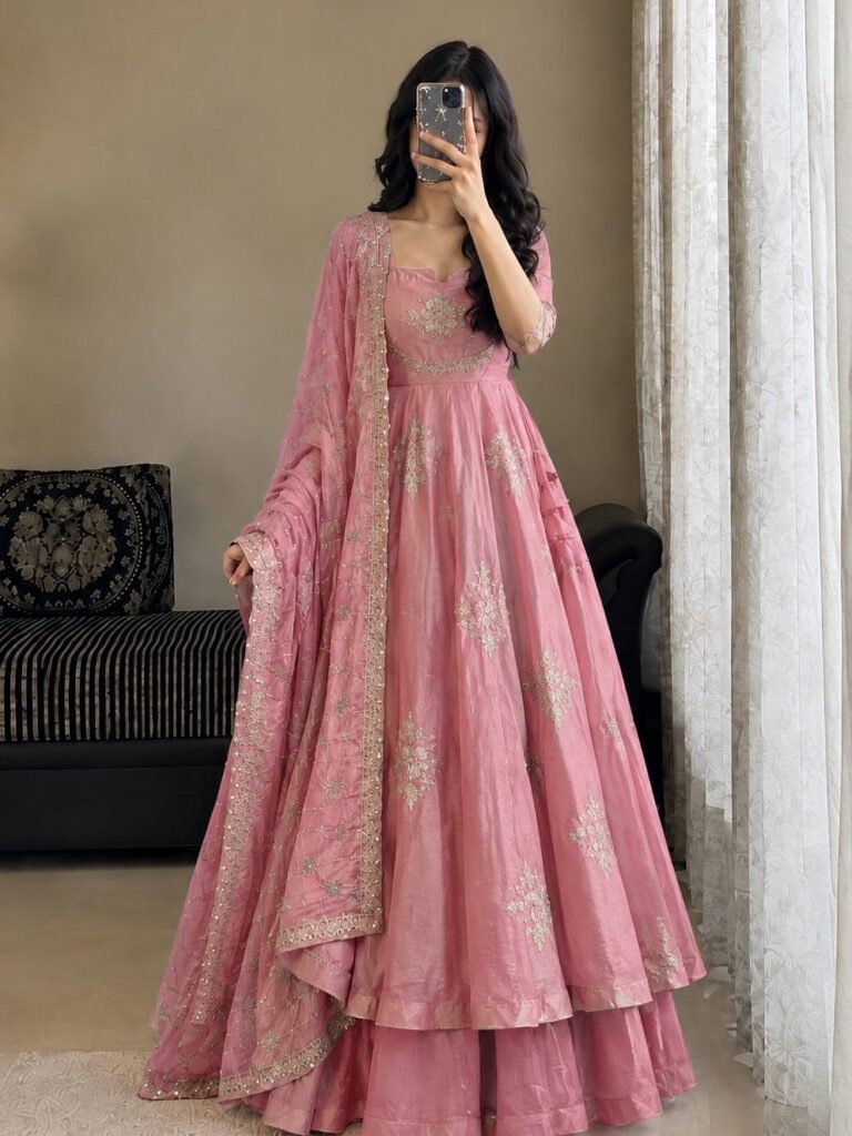 Woman wearing a pink embroidered lehenga choli and dupatta for a wedding guest outfit.
