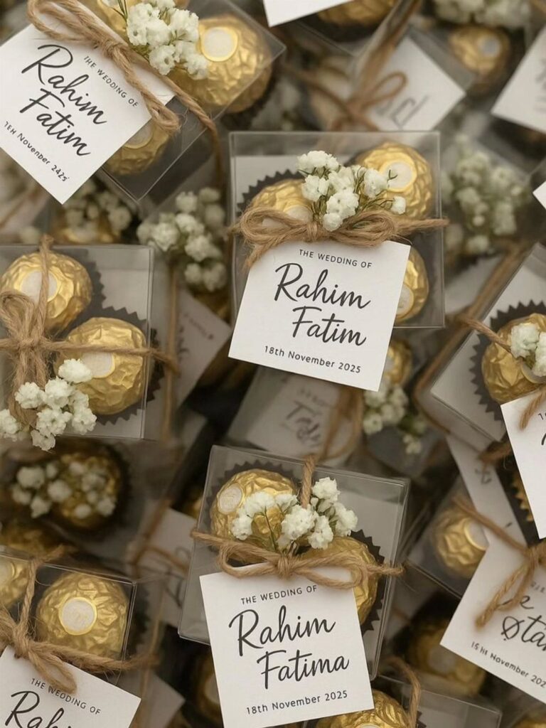 Gold wrapped chocolates in clear boxes with twine, baby's breath, and wedding tags.