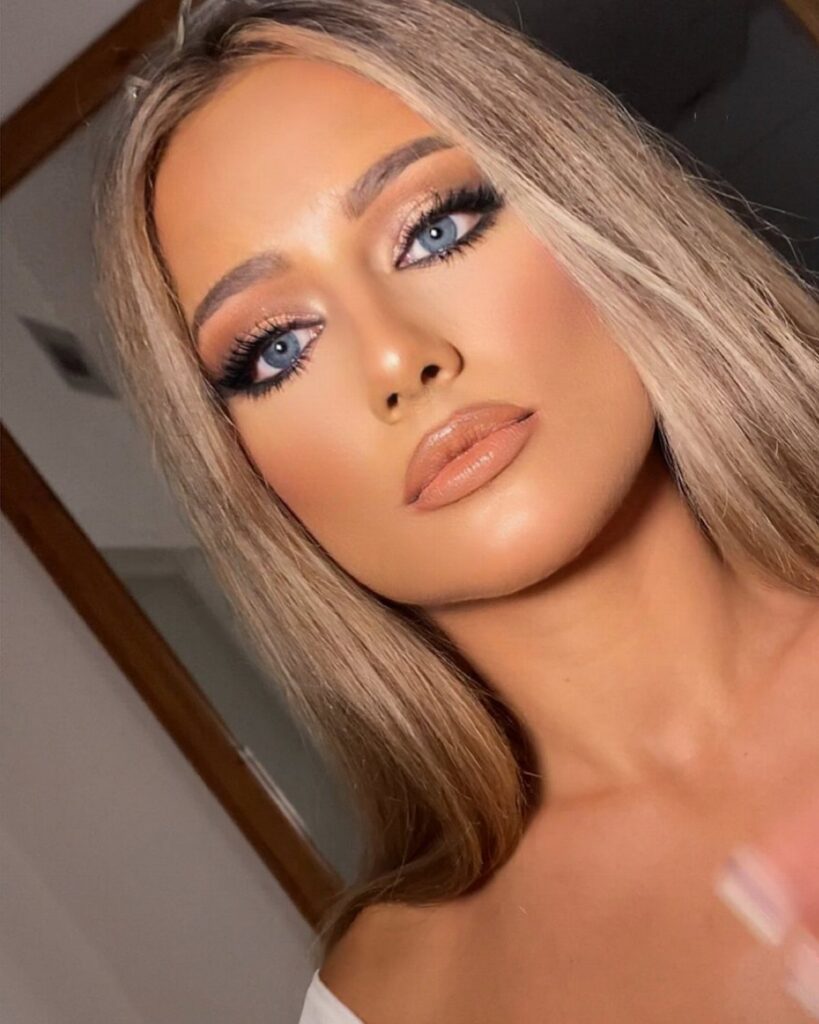 Woman with blue eyes wearing shimmering gold wedding makeup and nude lipstick