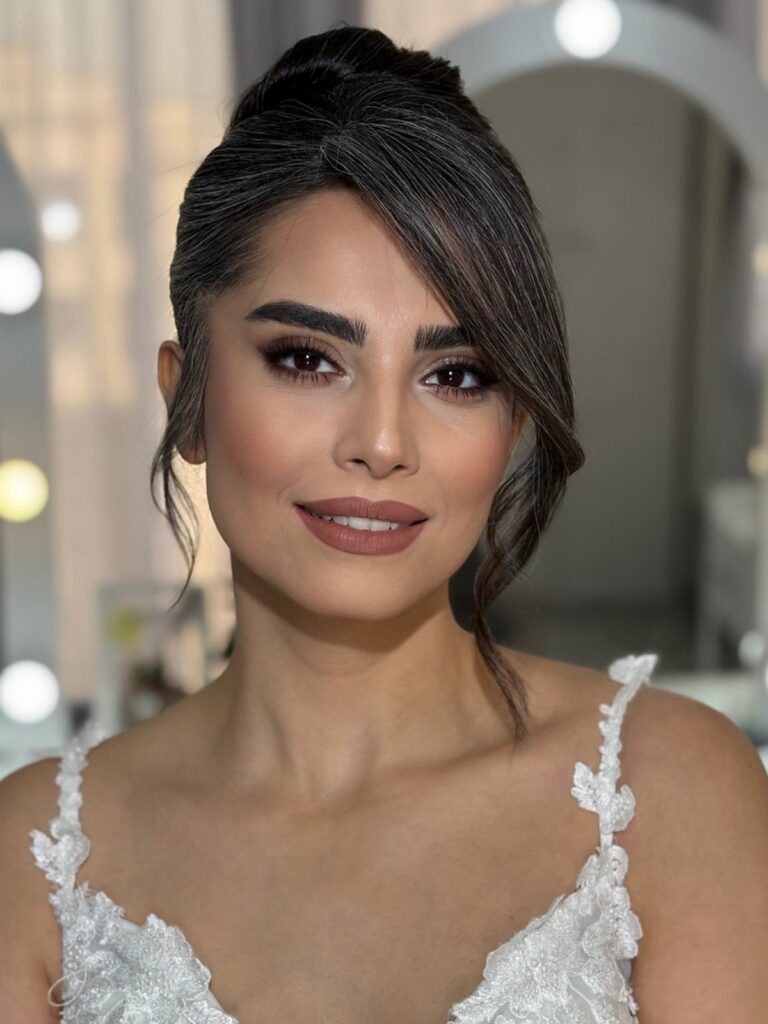 Woman with soft glam bridal makeup and an elegant updo wearing white lace.