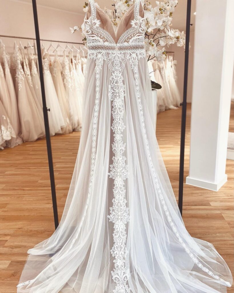 White boho wedding dress with lace embroidery and sheer tulle on a mannequin